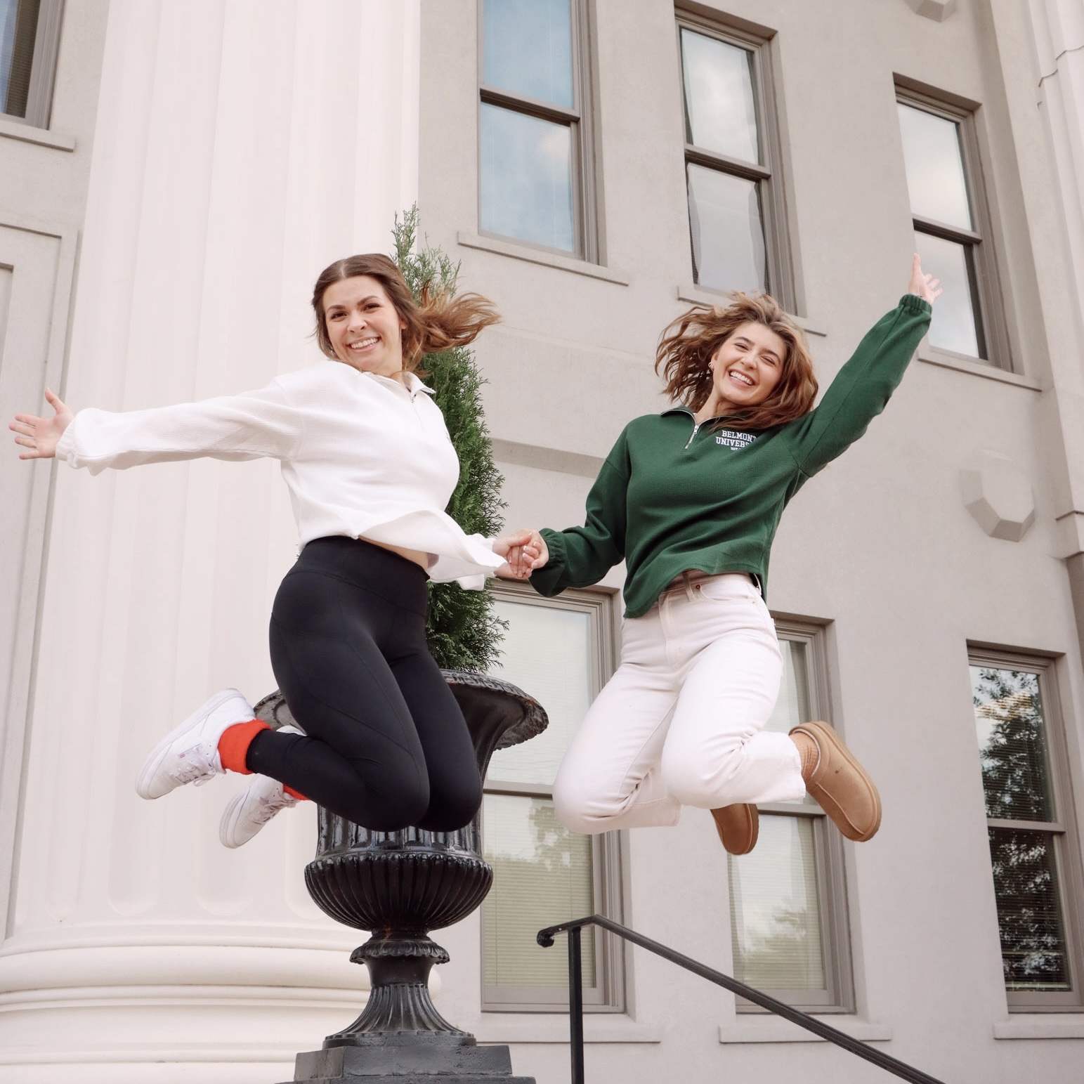 Two female Belmont Students holding hands and jumping. Click here to view on instagram. 