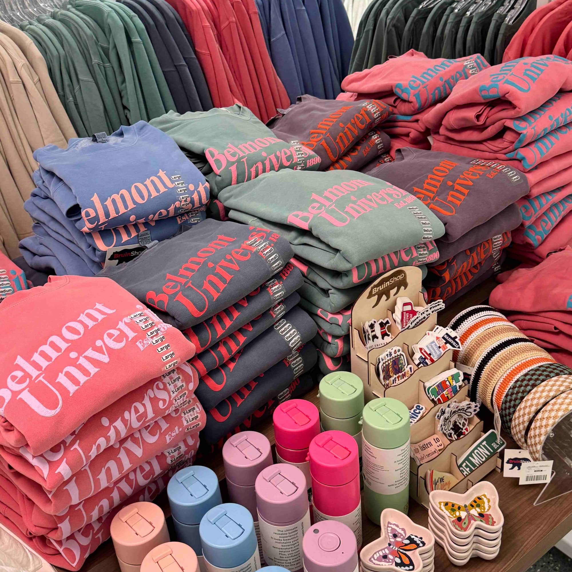 Image of Belmont BruinShop puff print crewneck sweatshirts and pastel colored water bottles. Click to view Instagram post